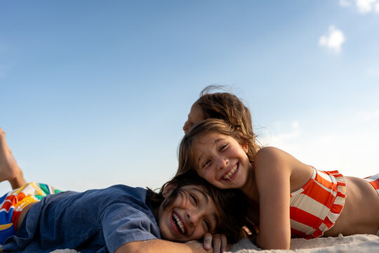 Children leaning together smiling down at camera, low angle. 