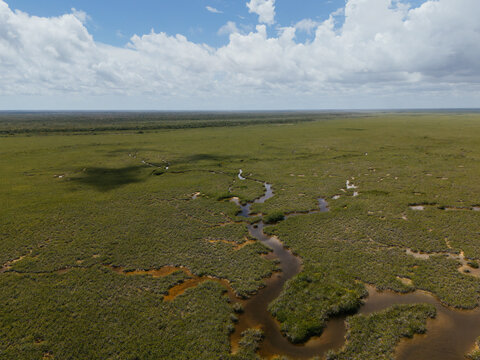 Narrow lagoon channel through wetland under cloudy sky