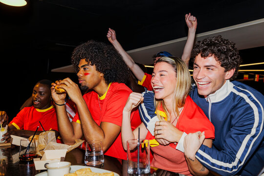 Diverse friends cheering for his team watching football game