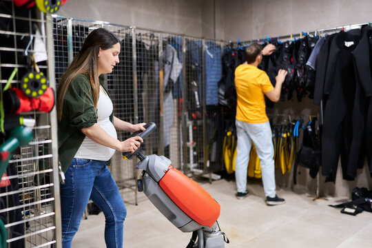 Pregnant woman cleaning dive center floor with equipment