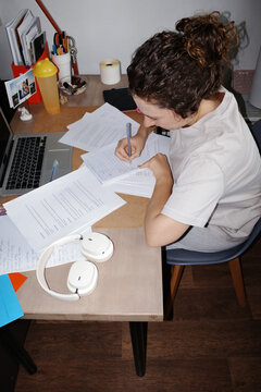 Person studying hard at messy desk writing notes