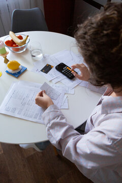Person budgeting home expenses using calculator and receipts