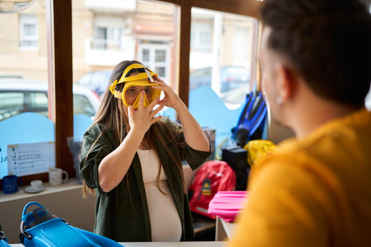 Pregnant woman trying scuba mask in dive center