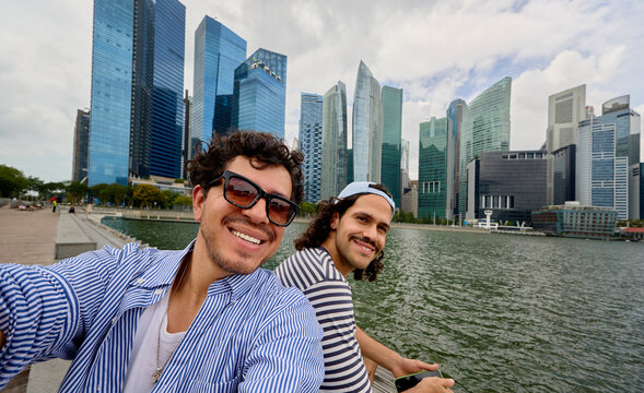 Friends taking selfie with Singapore skyline by Marina Bay