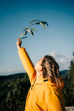 Woman Holds Leaves High Against Blue Sky in Nature Setting