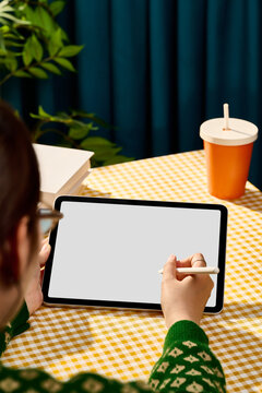 Person using a stylus on a tablet screen while sitting at a table