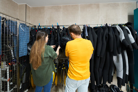 Woman showing diving equipment to man in dive center