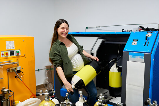Pregnant woman handling scuba tank at dive center