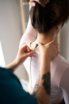 Physiotherapist applying neurostimulation electrode on patient neck