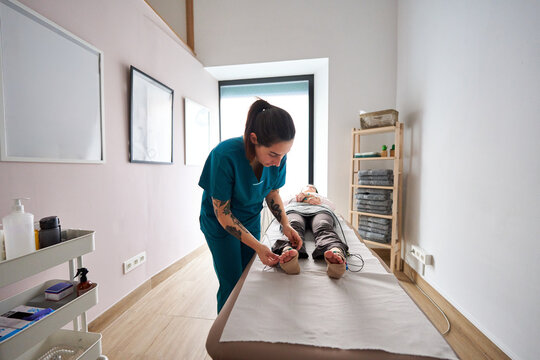 Therapist applying neurostimulation electrodes on patient's feet