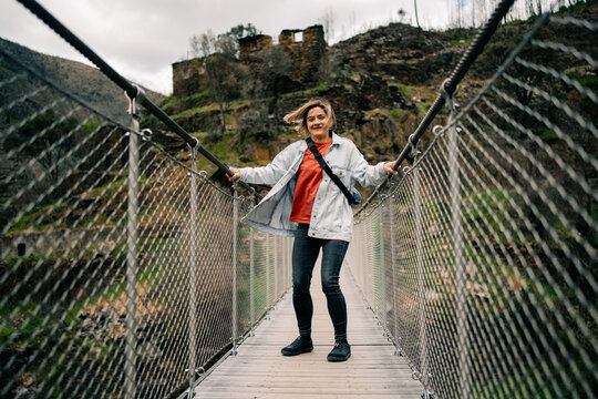Woman Stands on a Bridge in a Forest Area With Ruins Nearby