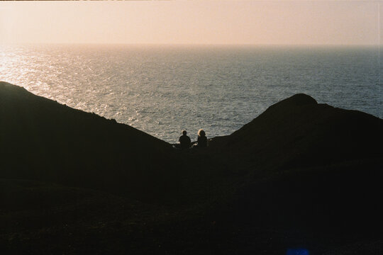 Unknown friends in silhouette observing sunset along Lanzarote&rsquo;s coast