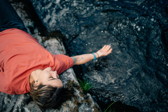Woman Relaxes by a Stream in Nature During a Sunny Day