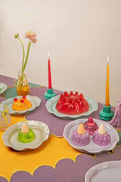 Colorful festive table setting with jelly desserts, candles and flower