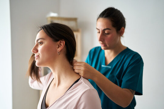 Physiotherapist using neurostimulation on patient's neck for recovery