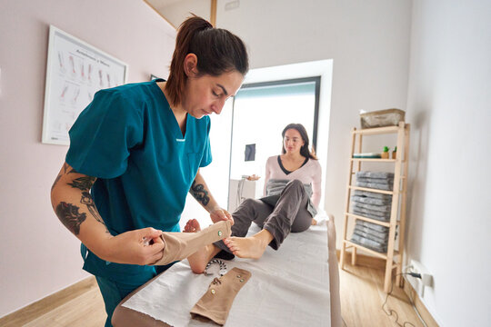 Physiotherapist applying neurostimulation device on patient's foot