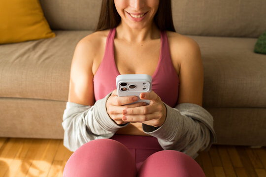 Girl exercises at home while using her phone on the floor    