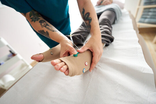 Physiotherapist attaching electrodes for neurostimulation