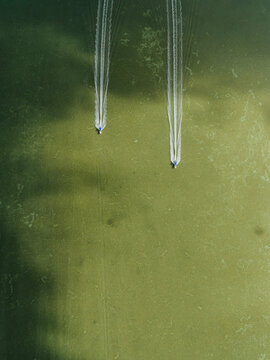 Two Boats Leave Trails on a Green Water Surface in a lagoon
