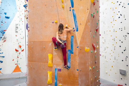 Young woman bouldering on indoor climbing wall