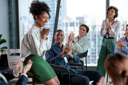 Diverse team applauds in modern office setting.