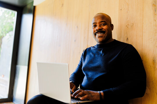 Man smiling working on laptop at office