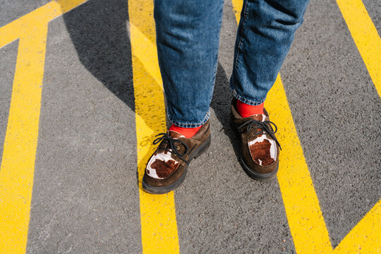 Brown shoes with red socks standing on bright yellow road