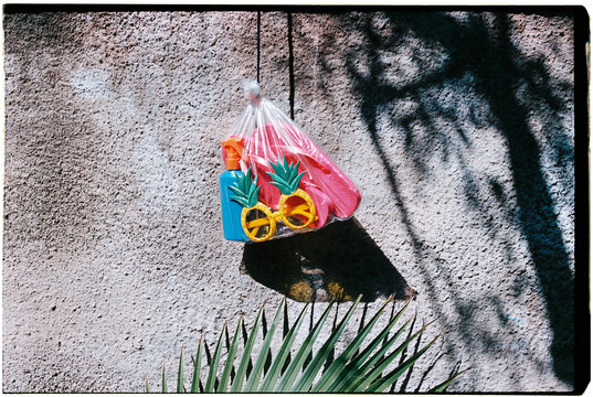 a bag with summer items hangs on a pool wall, 35mm film