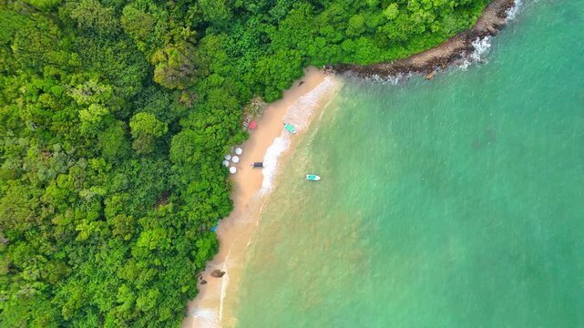 Aerial view of Jungle Beach featuring turquoise water, small boats, and golden sand bordered by lush green jungle in Southern Province, Sri Lanka.