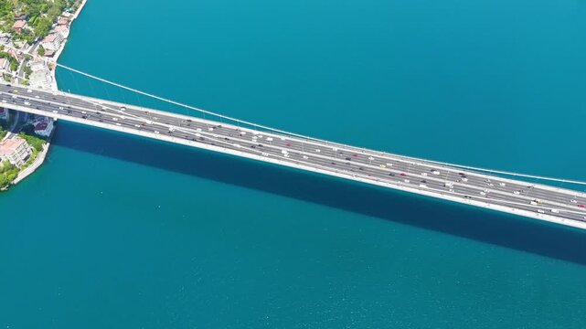 Istanbul, Turkey. Fatih Sultan Mehmet Bridge, a steel suspension span carrying eight lanes of traffic across the deep turquoise Bosphorus Strait, aerial top-down view on a bright sunny day. Aerial Vi