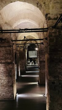 Majestic gallery of ancient Nakkaş Cistern underground museum in Istanbul, Turkey. Roman empire brick arches with illuminated path, old stone walls and exhibition in background. Byzantine travel.