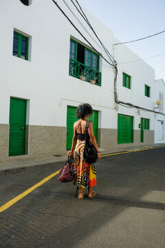 Woman walking down street with bags in sunny location