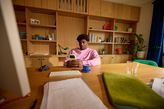 Man sits back at his desk, uses the phone