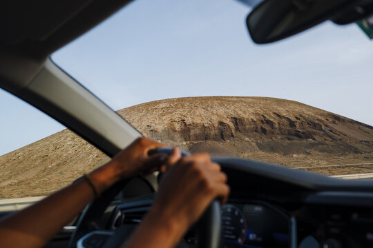 Driving on a road with a large hill in the background