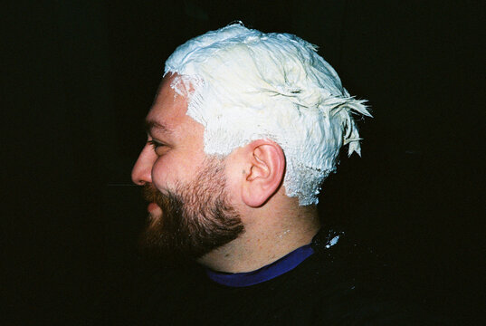 Side profile of man during hair bleaching