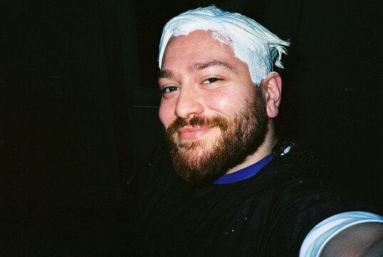 Smiling man with bleach on hair looking at camera