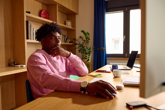 Portrait of a man is seated at a desk, focused on his computer
