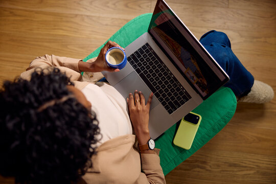Woman uses her laptop while holding a cup of coffee