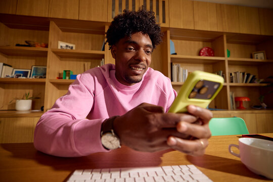 Man sends text messages on his phone while at his desk