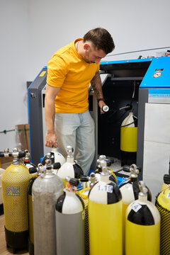 Man filling compressed air scuba tanks at dive center