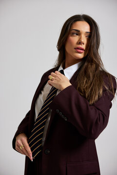 Model poses in a suit with a tie in a studio setting