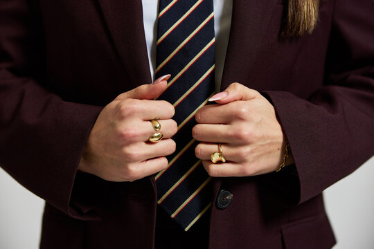 Person adjusts tie while wearing a suit in a simple setting