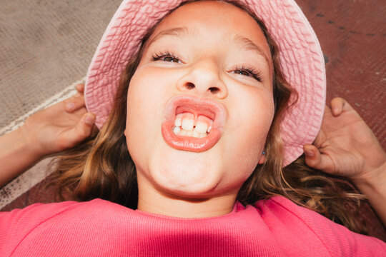 Playful girl making funny face showing teeth outdoors