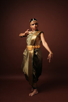 Traditional bharatanatyam dancer performing mudra on brown background