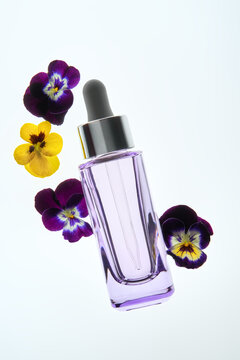 Purple Dropper Bottle With Flowers on Light Background with Copy Space