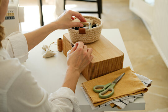 A closeup of a person selecting colorful threads from a small box.