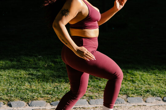 Anonymous curvy female athlete running on a park