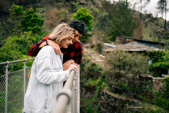 Couple Embraces on Bridge Overlooking Lush Landscape in Day Time