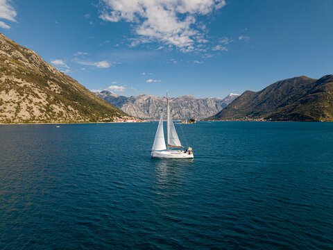A Sailboat with white sails in Bay of Kotor, Perast