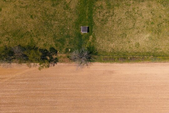 Top view of small shed between grass and plowed field
